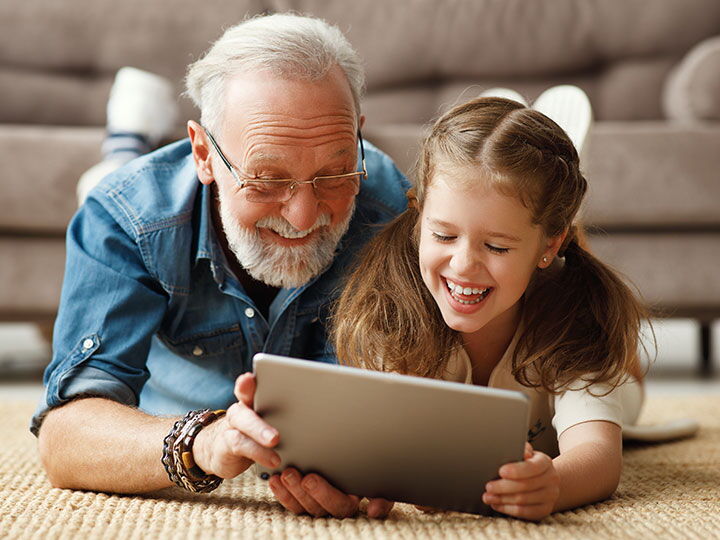 Großvater und Enkelin genießen gemeinsam digitale Unterhaltung auf einem Tablet.